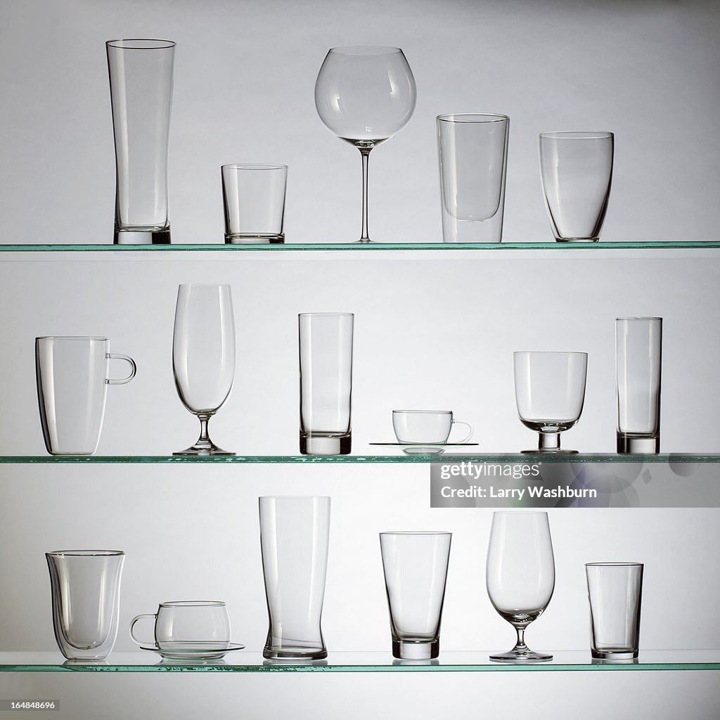 A collection of various types of drinking glasses arranged neatly on three shelves