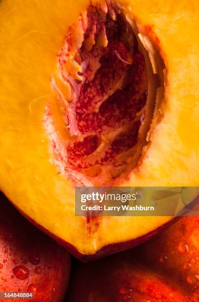 half of a juicy peach resting on two uncut peaches, full frame - juicy stock pictures, royalty-free photos & images