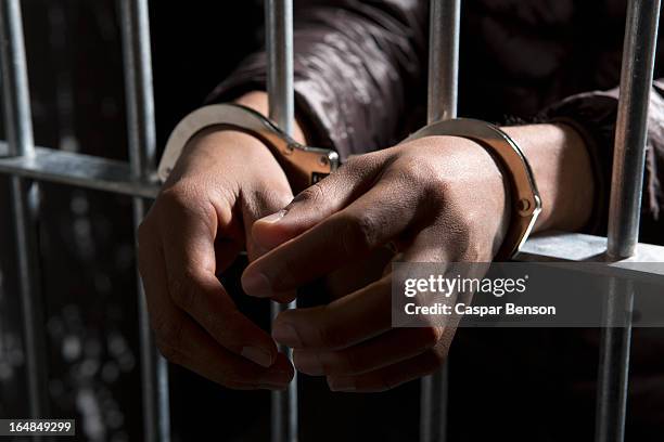a prisoner behind bars with hands cuffed - handcuff of - fotografias e filmes do acervo