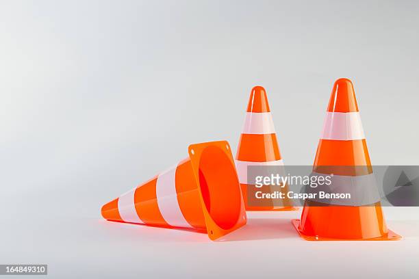 a traffic cone lying on its side next to two standing traffic cones - pylons stockfoto's en -beelden