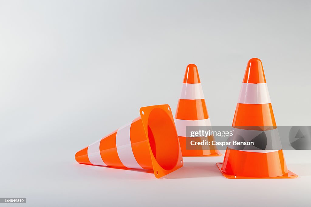 A traffic cone lying on its side next to two standing traffic cones