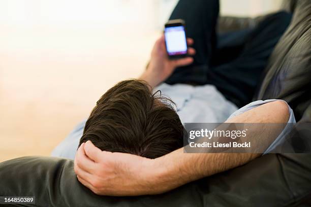 a man lying on a sofa looking at smart phone, view from top of head - top of head stock pictures, royalty-free photos & images