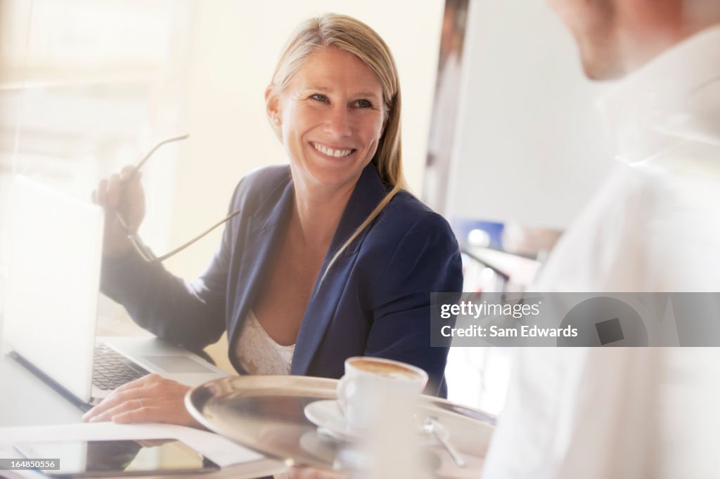 Mulher de Negócios sorridente com Empregado de Mesa no restaurante