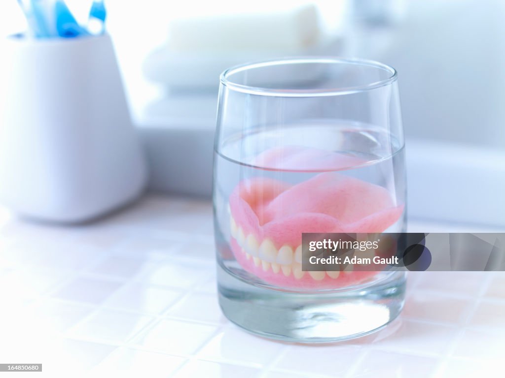 Close up of dentures soaking in glass of water