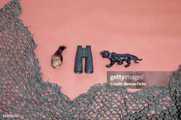 a shrunken head, binoculars, a jaguar and camouflage netting - netzgewebe stock-fotos und bilder