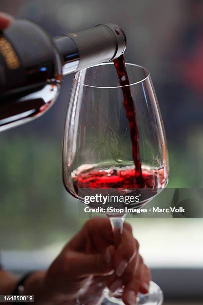 a woman pouring a sampling of red wine at a wine tasting, focus on hands - red wine foto e immagini stock