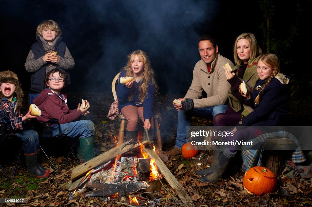 Famille manger autour de feu de camp à la nuit