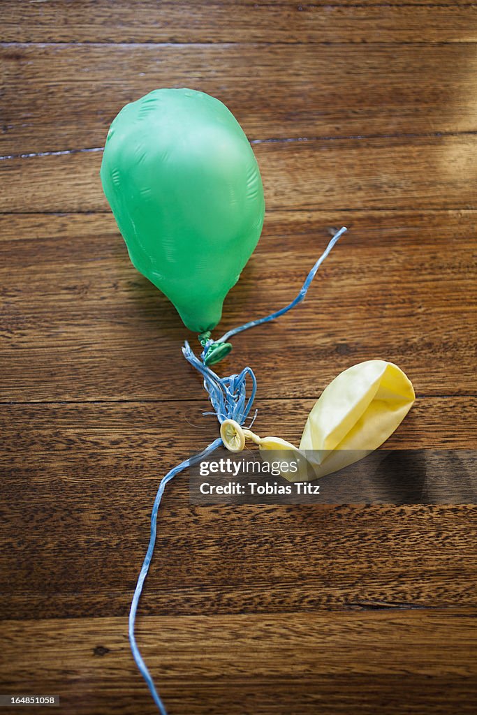 Two deflated balloons on a wooden table