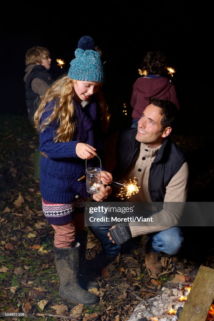 Father and daughter playing with sparkler