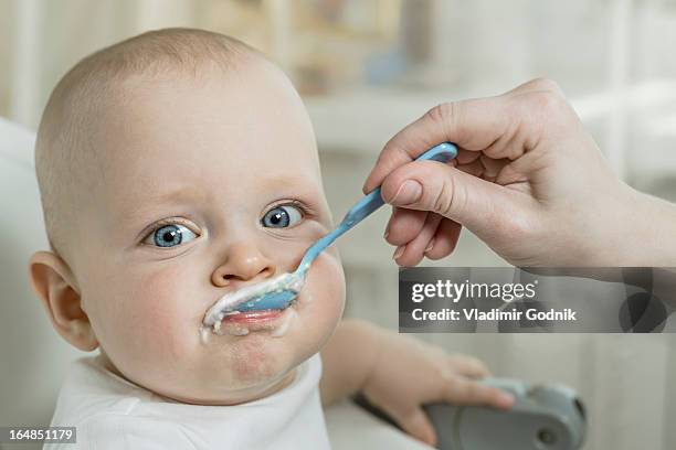 mother spoon feeding son - spoon feeding stockfoto's en -beelden