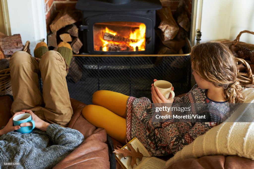 Children drinking cups of tea by fire