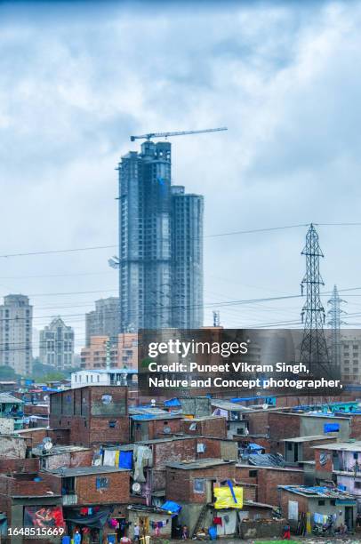 a juxtaposed image of mumbai slums against the backdrop of under construction multistorey building indicating a connection between formal and informal economy - indian society and culture stock-fotos und bilder