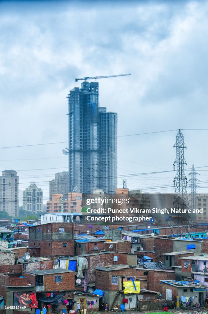 A juxtaposed image of Mumbai Slums against the backdrop of under construction multistorey building indicating a connection between formal and informal economy