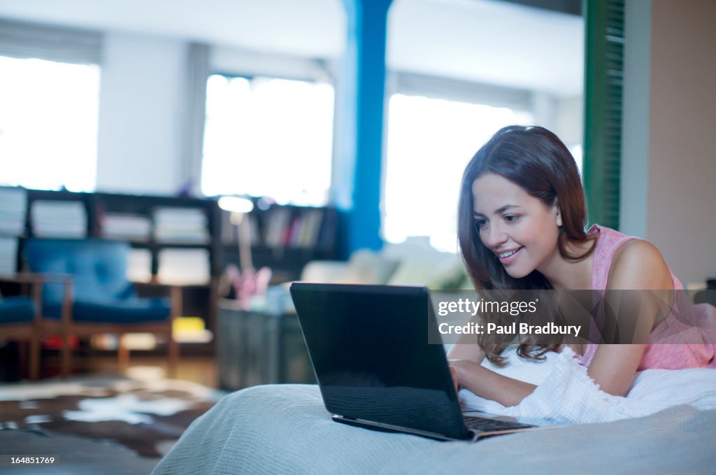 Mulher na cama com computador portátil