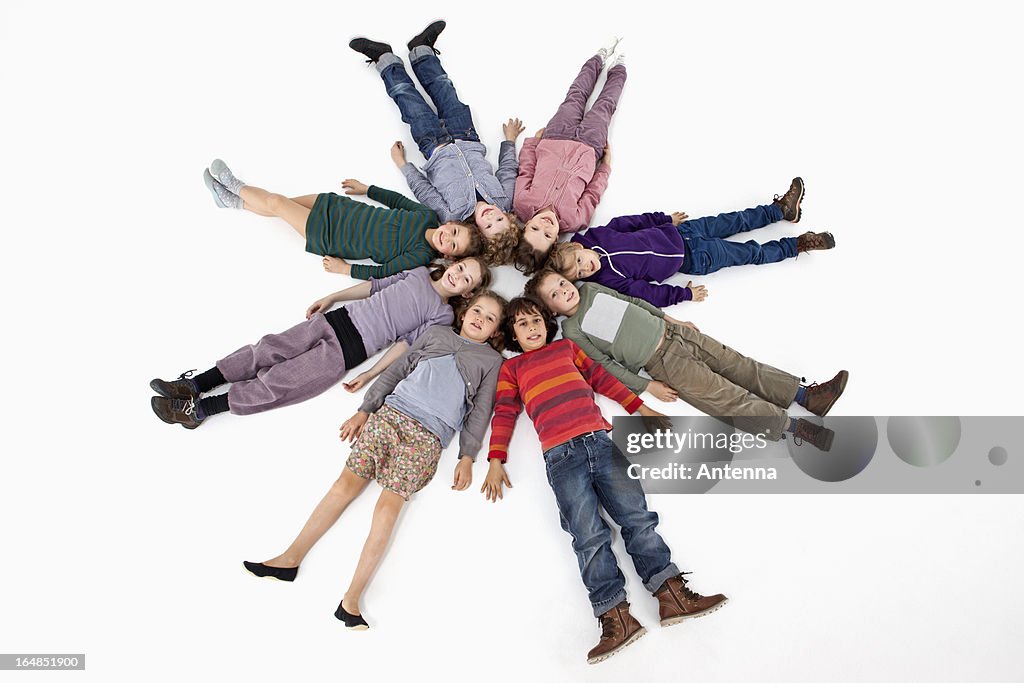 A group of kids lying on their backs in a circle