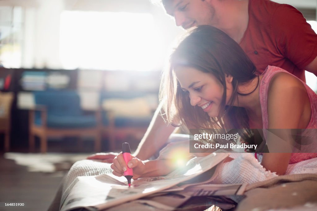 Couple reading newspaper together on bed