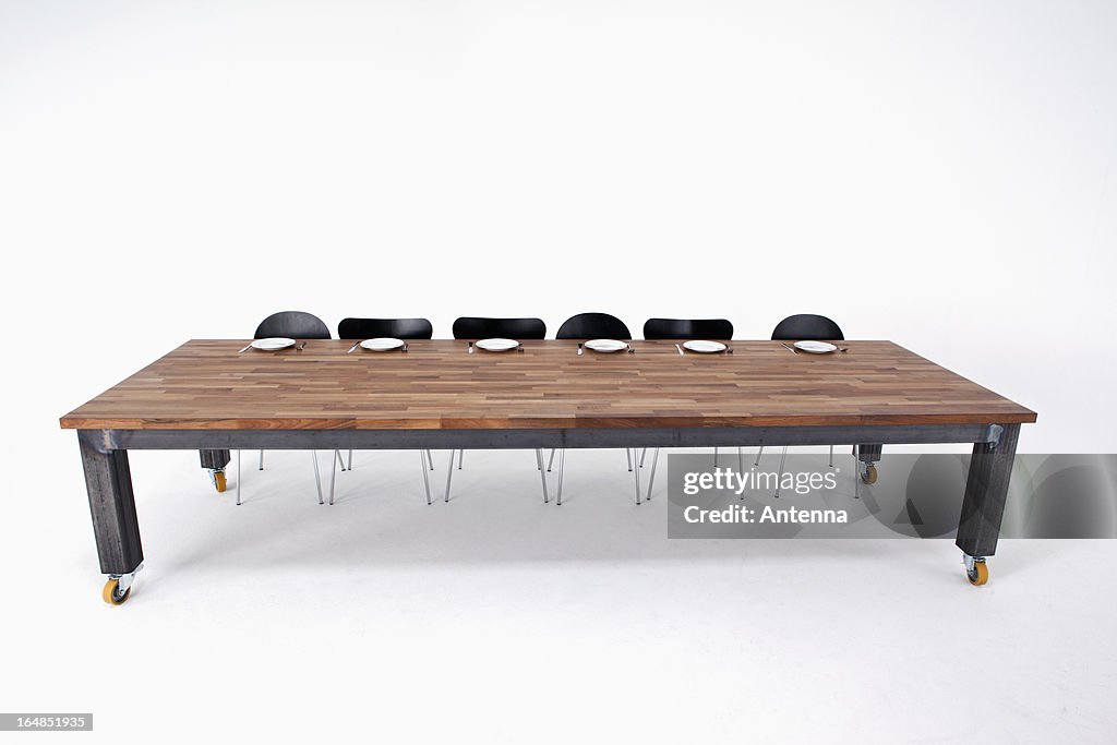 A large wood table with six chairs and six empty place settings