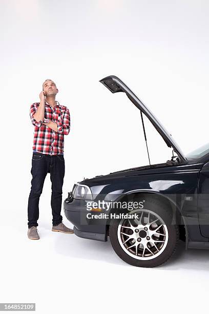 a man standing next to broke down car, using a cell phone and looking impatient - car broken down stock-fotos und bilder