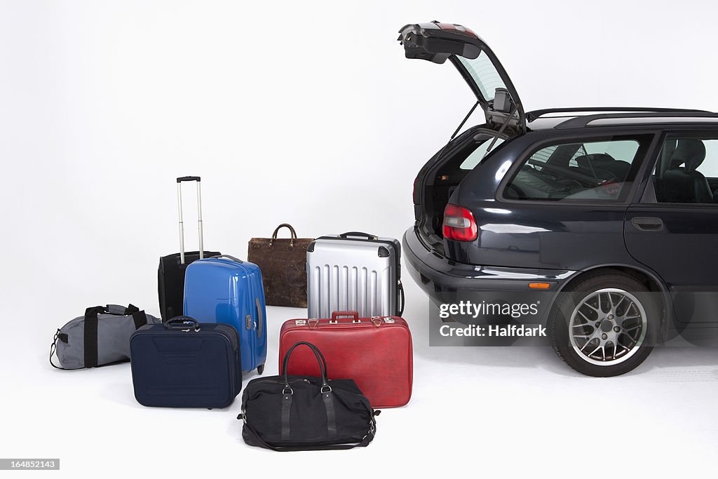 A bunch of different pieces of luggage next to an open car trunk