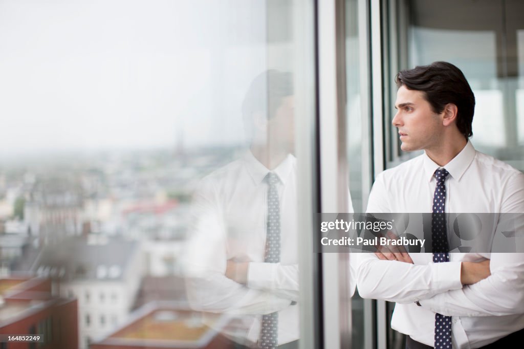 Empresario mirando por la ventana de oficina