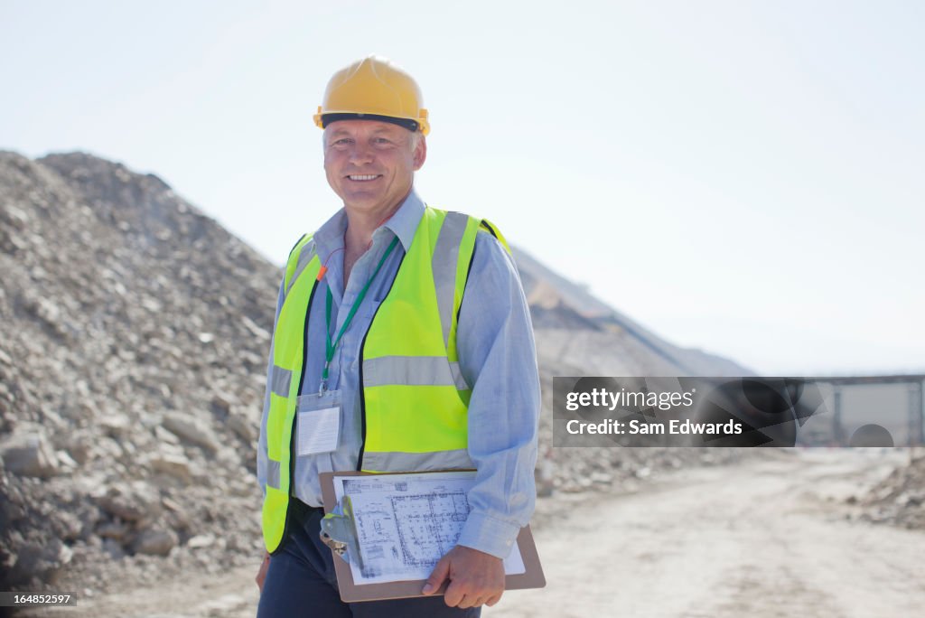 Businessman carrying clipboard in quarry