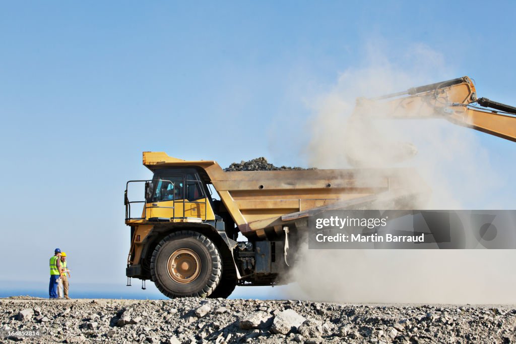 Trabalhadores supervisionando digger e camião na Pedreira