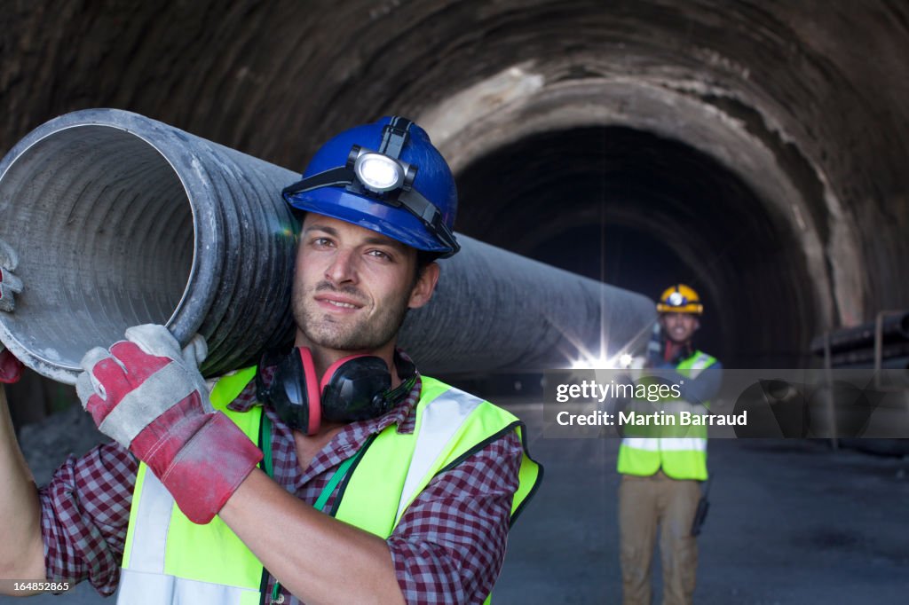 Os trabalhadores transportem tubo comprido no túnel