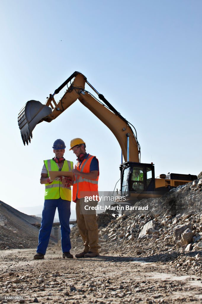 Workers talking by digger in quarry