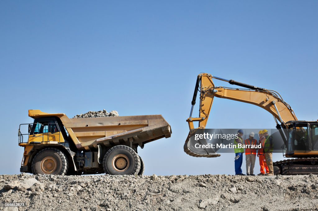 Workers talking by machinery in quarry