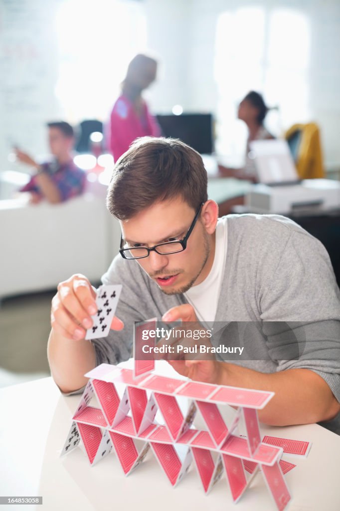 Businessman making house of cards in office