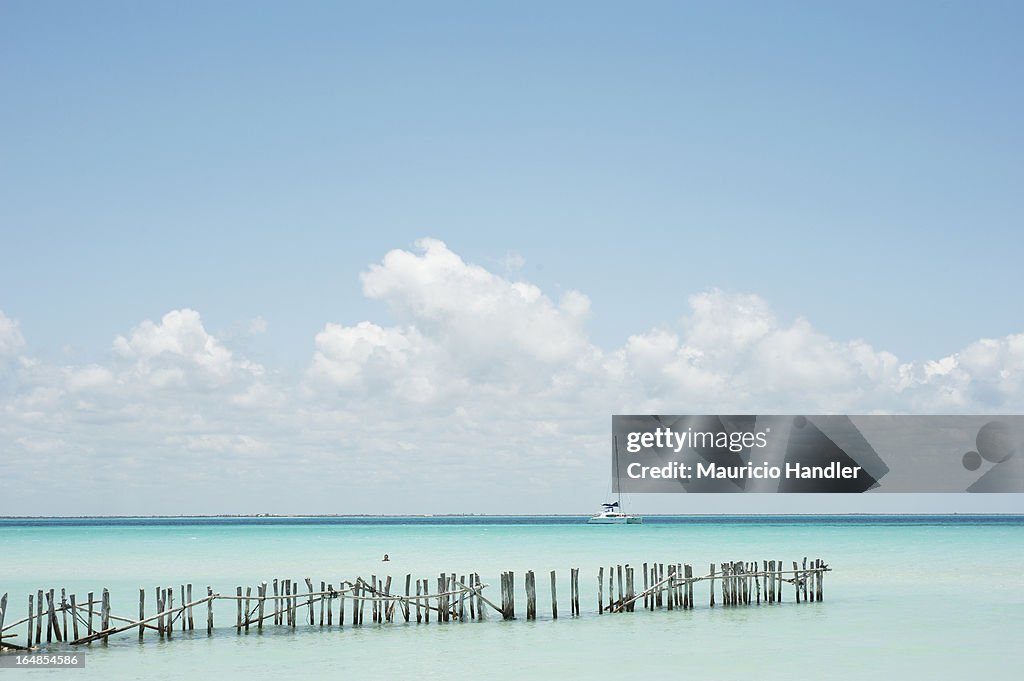 Piling remains and a sailboat in the Caribbean at Isla Mujeres.