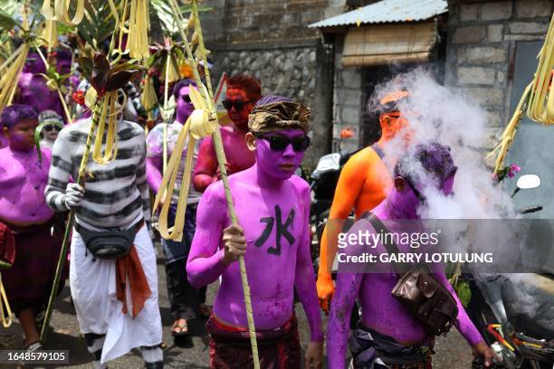 Men body-painted as scary mythical creatures symbolizing the balance between darkness and light march on the street as they practice their Hindu...
