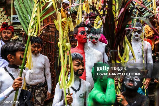 Men and boys body-painted as scary mythical creatures symbolizing the balance between darkness and light march on the street as they practice their...