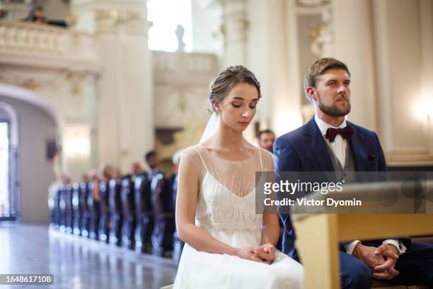 attentive newlyweds in the spacious bright church - indoor wedding ceremony stock pictures, royalty-free photos & images