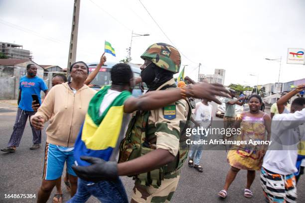 Joyful Gabonese embracing a Republican Guard soldier in front of the presidency in Port-Gentil , on August 30, 2023 after the announcement of the...