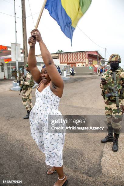 Gabonese woman in joy in front of a Republican Guard soldier on duty at the presidency in Port-Gentil , on August 30, 2023 after the announcement of...