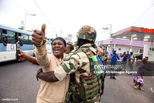 Joyful Gabonese woman embracing a soldier of the Republican Guard in front of the presidency in Port-Gentil , on August 30, 2023 after the...