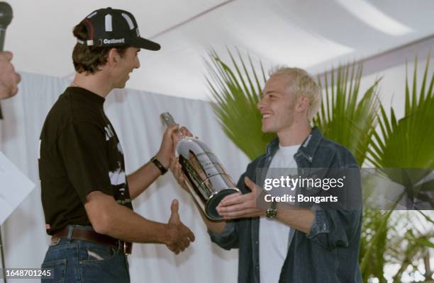 British racing driver Damon Hill presents Canadian racing driver Jacques Villeneuve with a silver bottle of champagne following the European Grand...