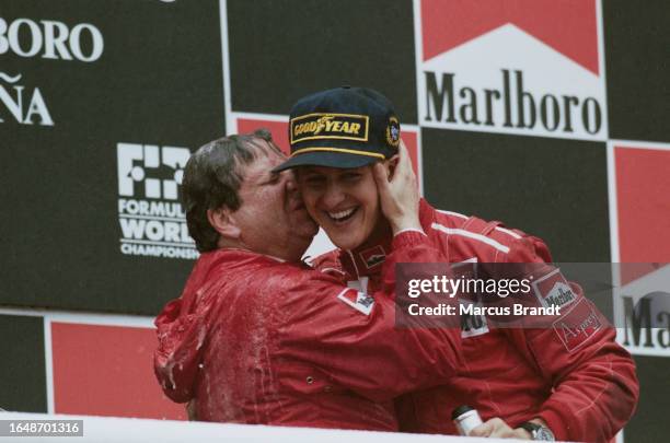 French motor racing executive Jean Todt, General Manager of Scuderia Ferrari, with German racing driver Michael Schumacher, wearing red coveralls and...