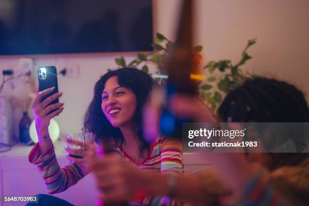 grupo de felices amigos multiétnicos tomando unas copas disfrutando de la música en casa en la fiesta navideña - party friends home guitar singers fotografías e imágenes de stock