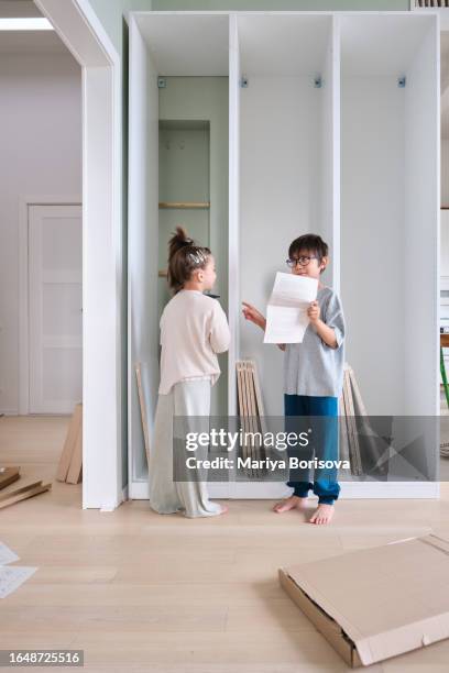 a boy and a girl collects a closet in a bright room at home. - cleaning up after party stock pictures, royalty-free photos & images