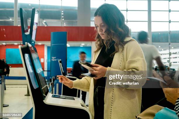 young woman doing self check in - self service stockfoto's en -beelden