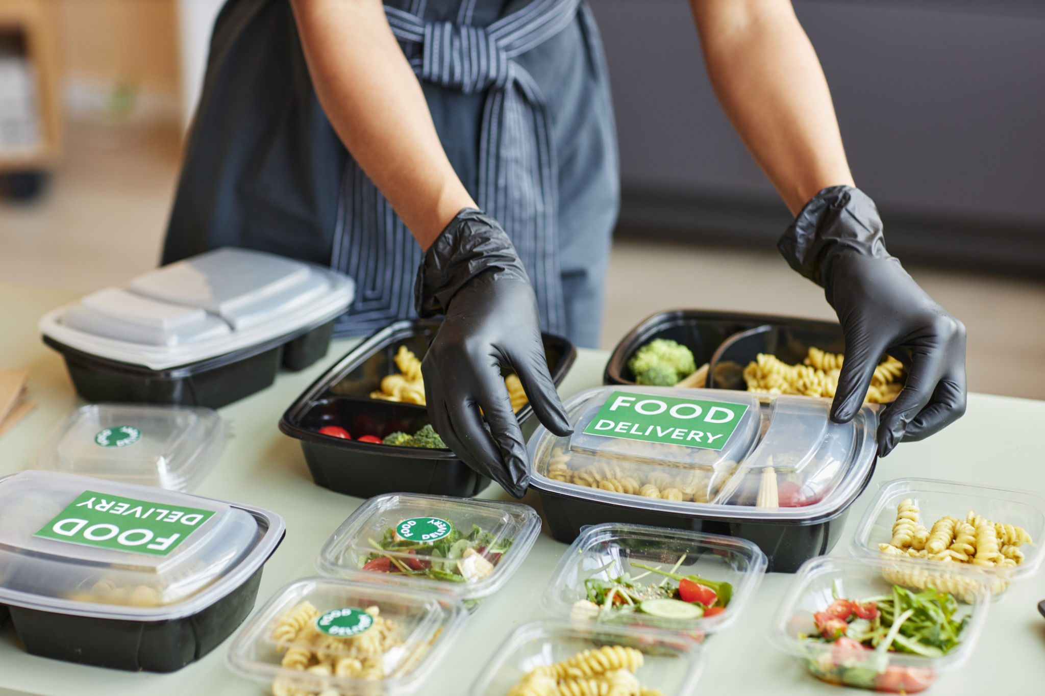 Woman carefully packing food delivery orders in PLA containers Woman carefully packing food delivery orders in PLA containers