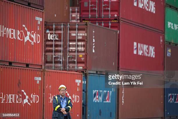 Member of security staff stands in front of stacked containers at the Kwai Chung Container Terminal on March 29, 2013 in Hong Kong, China. Over 100...