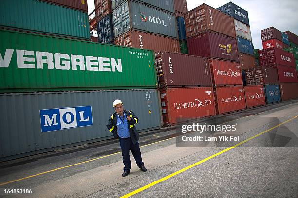 Member of security staff stands in front of stacked containers at the Kwai Chung Container Terminal on March 29, 2013 in Hong Kong, China. Over 100...