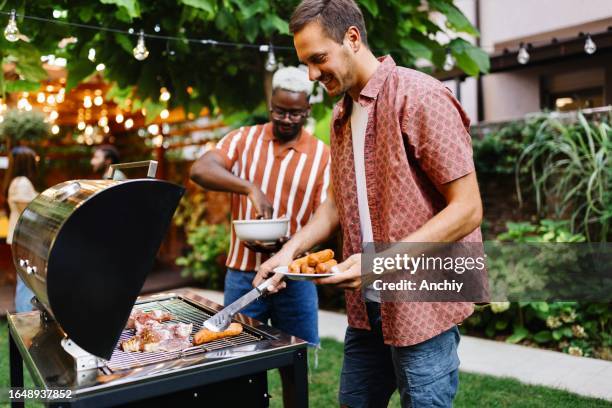 zwei männliche freunde, die ein barbecue zubereiten - grillfleisch stock-fotos und bilder