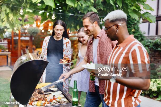 schöne gruppe von menschen, die einen grill vorbereiten - grillfleisch stock-fotos und bilder