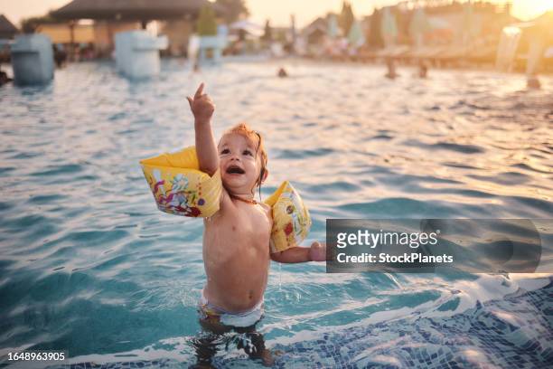 niña divirtiéndose en una piscina - brazaletes acuáticos fotografías e imágenes de stock