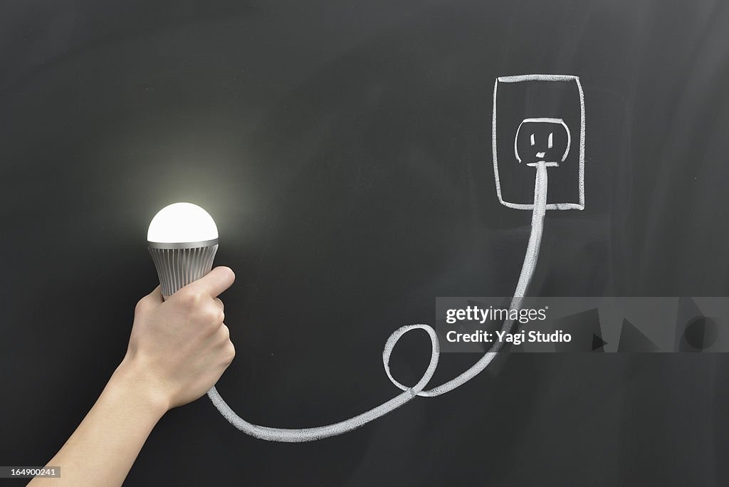 Hand holding a light bulb and the outlet