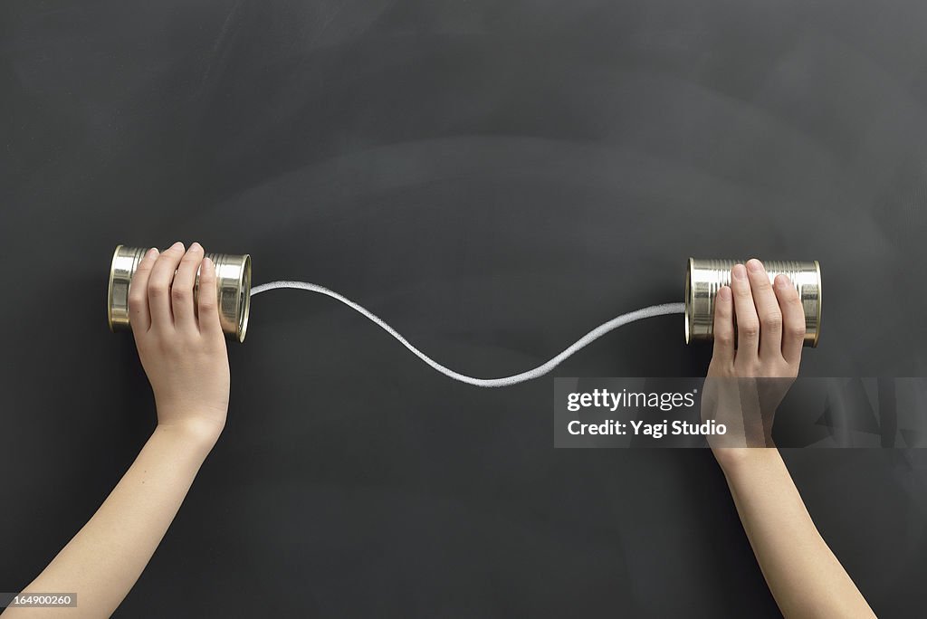 Hands holding the cans on a blackboard